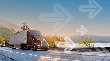 A red semi-truck drives along a highway by a scenic lake at sunrise. Mountains and trees surround the road. Transparent arrows point forward across the image.