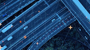 Aerial view of highways intersecting with several cars driving. The scene is overlaid with thin blue lines and scattered orange crosses, suggesting a digital or tech theme. Surrounding areas show some vegetation.