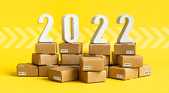 Stacks of small cardboard boxes on a yellow background with large white numbers 2022 placed on top of them.