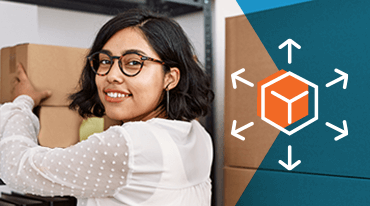 A person with glasses smiles while lifting a cardboard box in a storage area. To the right, there is a graphic of an orange cube with arrows pointing outward, symbolizing logistics or distribution.