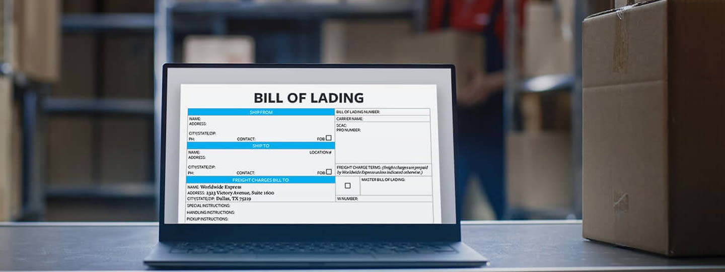 with shelves and a person blurred in the background.|A laptop on a warehouse table displays a bill of lading form on its screen. Cardboard boxes and shelves are visible in the background