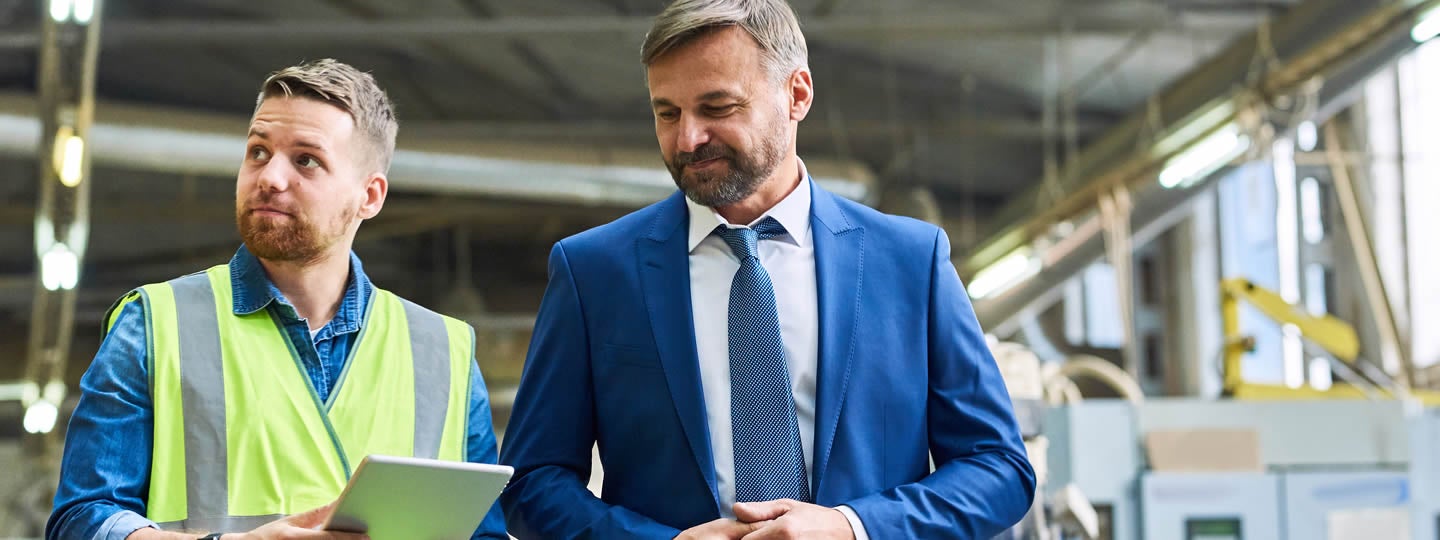likely a bustling small-business-shipping-hub. The safety vest man gestures animatedly while talking. To the left