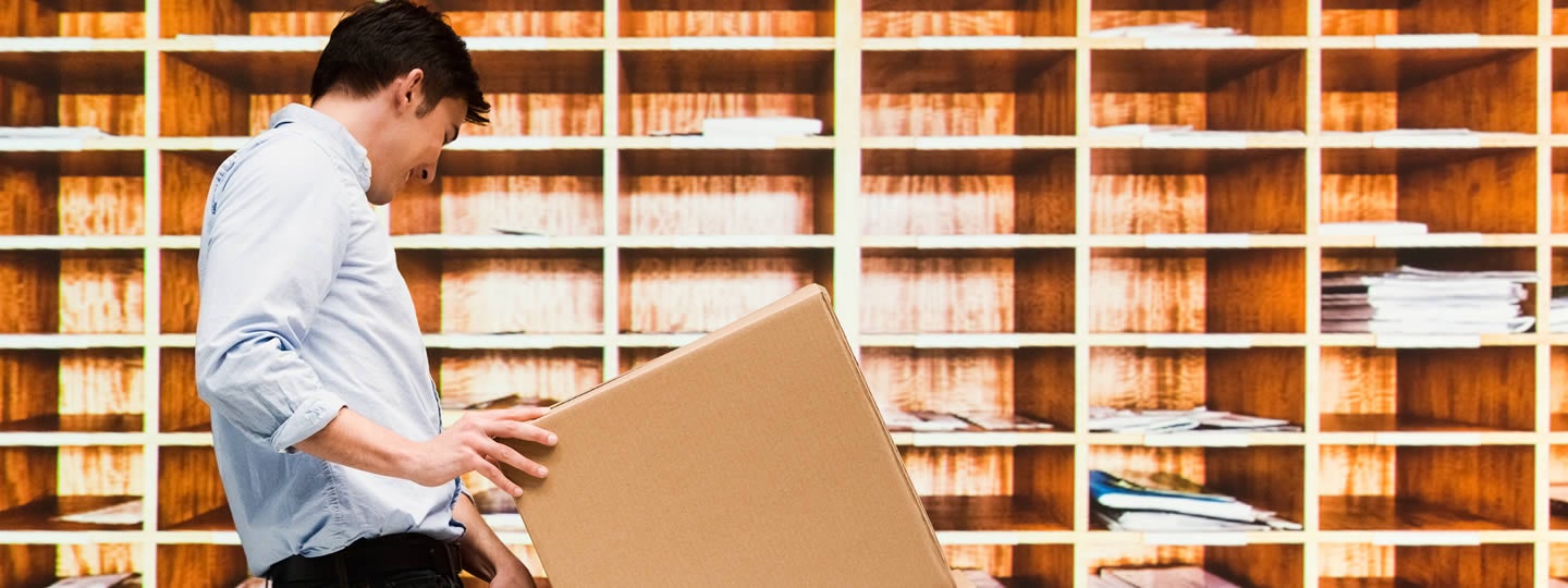 a green measuring tape graphic hints at the precision of a small-business shipping hub.|A delivery person pushes a hand truck loaded with boxes