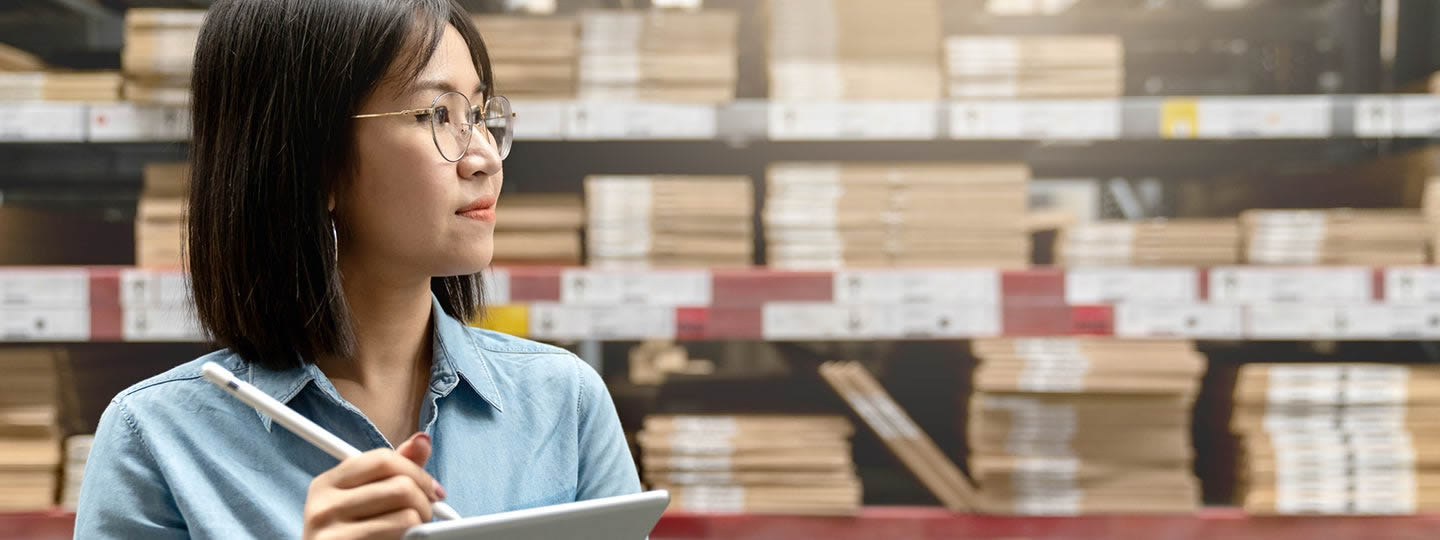 gazing thoughtfully to the side. Shelves with books or files fill the background
