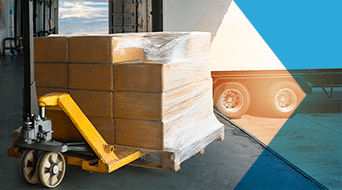A stack of cardboard boxes wrapped in plastic rests on a pallet jack at a small-business-shipping-hub. Positioned by the loading dock