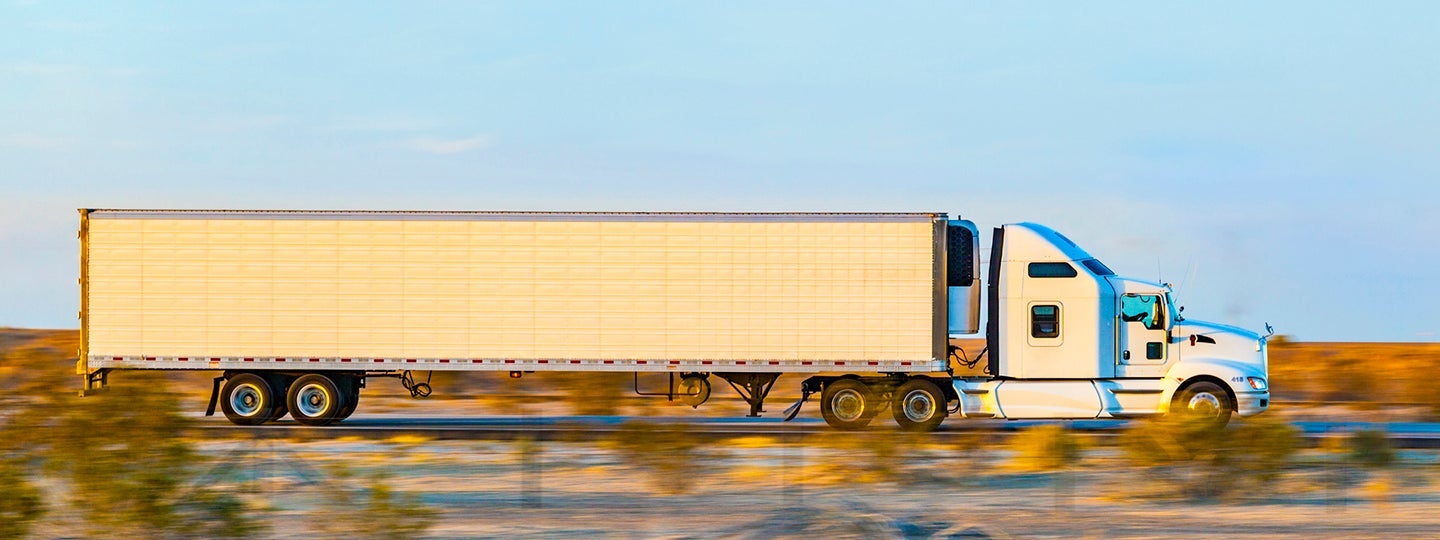 indicating motion. Orange geometric arrow patterns are overlaid at the top of the image.|A white semi-truck