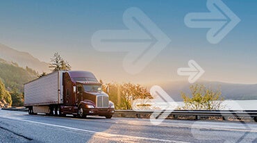 A red semi-truck drives along a highway by a scenic lake at sunrise. Mountains and trees surround the road. Transparent arrows point forward across the image.|A red semi-truck from our Guide to Freight Equipment series navigates a scenic lakeside road