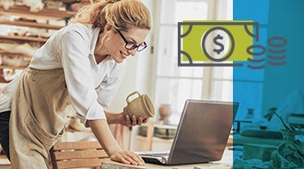 A woman in an apron holds a cup and looks at a laptop