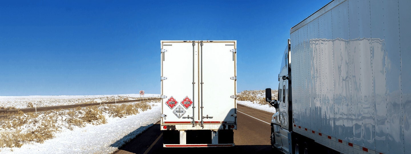 traveling alongside a semi-truck on a clear day. The road curves slightly to the left