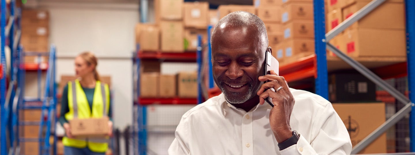 with one hand resting on her chin.|In a bustling warehouse filled with boxes and shelves