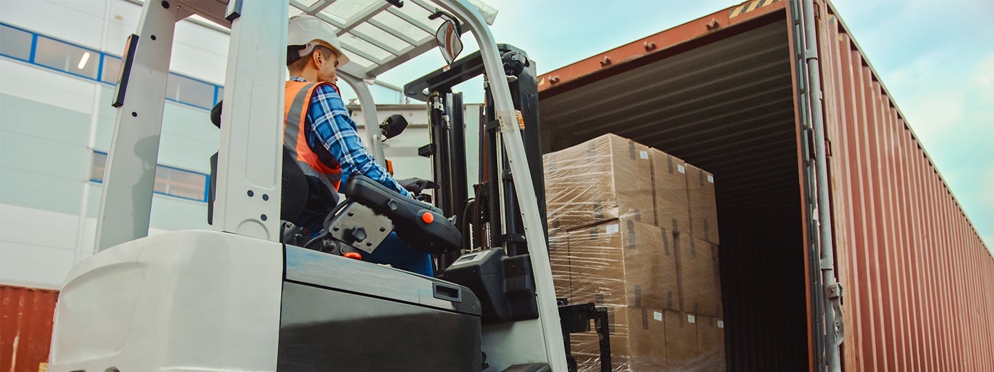 loading wrapped pallets into a shipping container. Blue arrows overlay the image