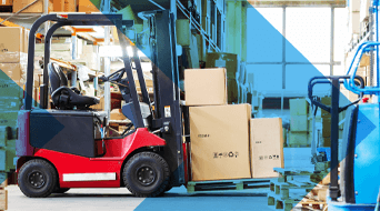 A red forklift is efficiently maneuvering a stack of cardboard boxes