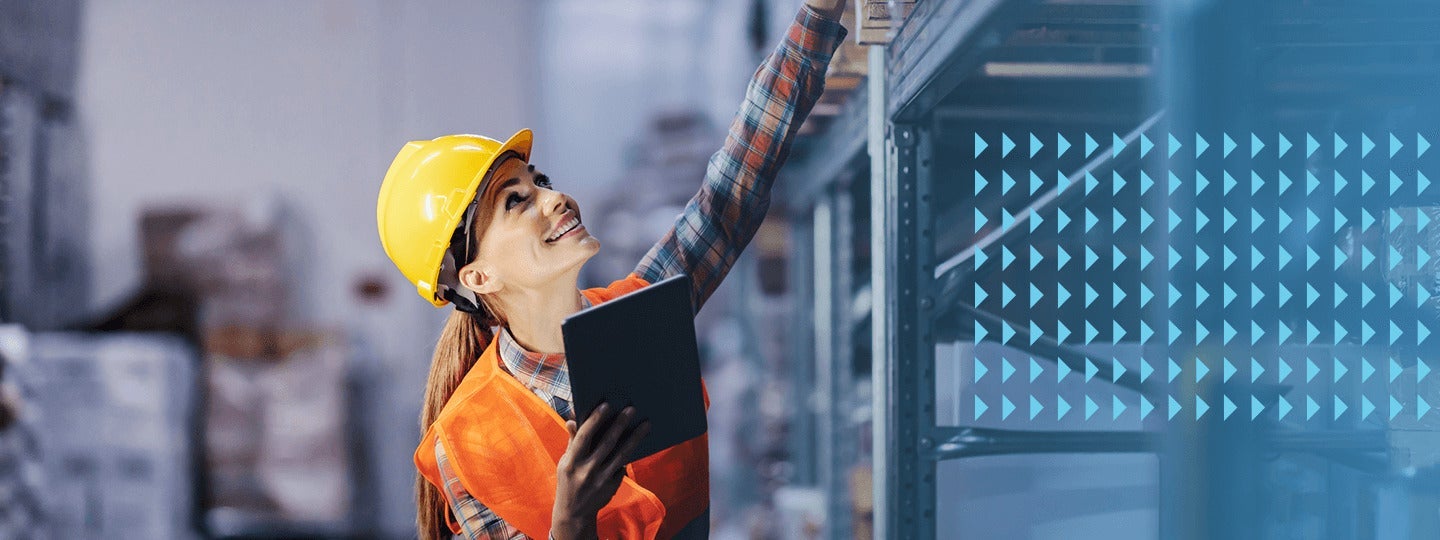 a person in a yellow hard hat and orange safety vest wields a tablet with one hand