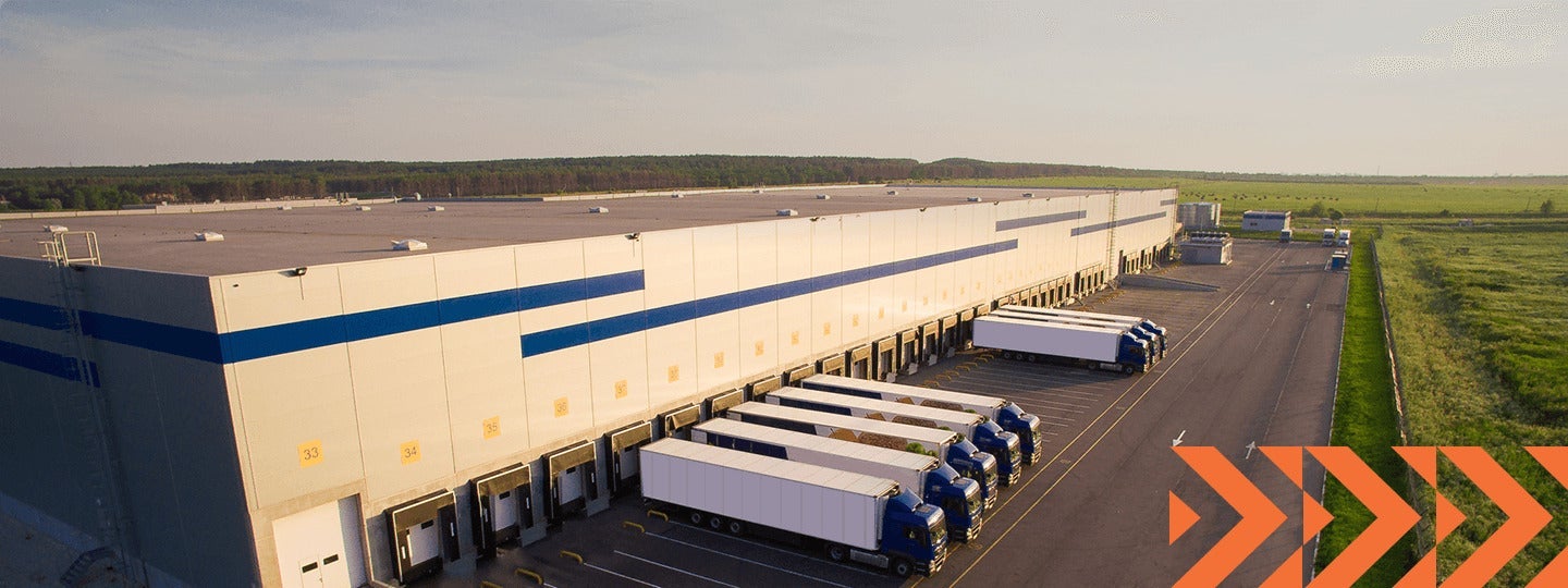 there are orange arrow patterns. The sky is clear.|A large distribution warehouse