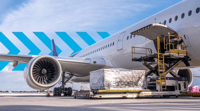 An airplane side view on an airport tarmac with an open cargo door. A cargo loading vehicle is positioned next to the plane