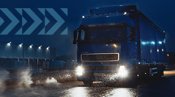 A large blue truck drives through a rainy