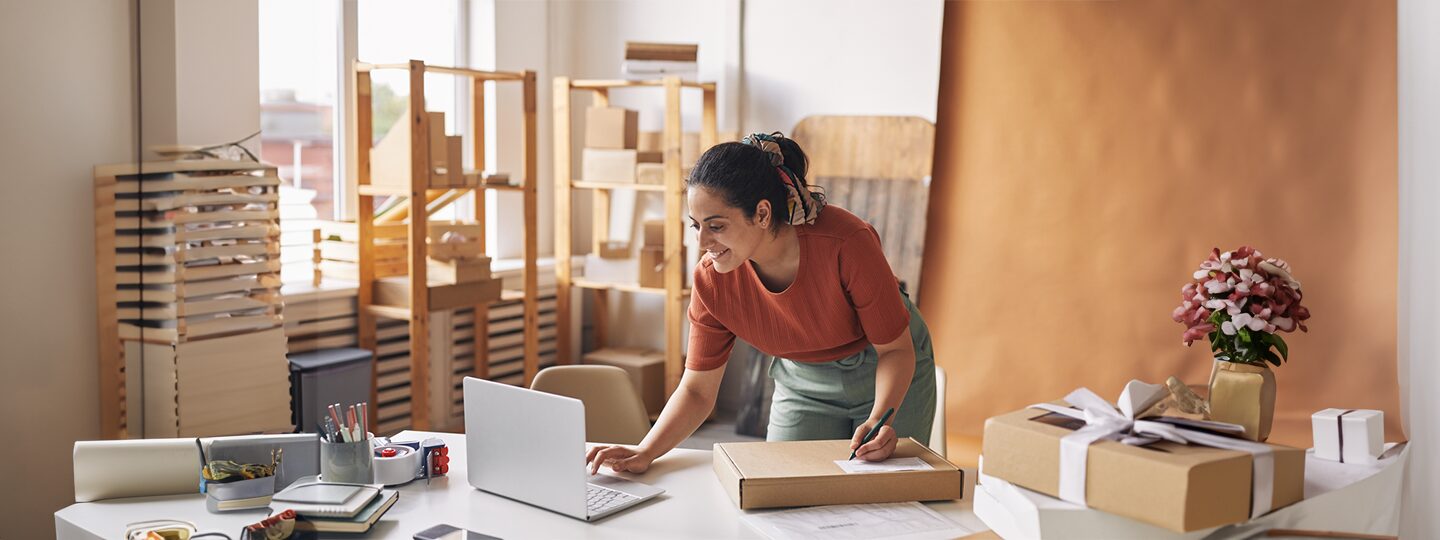using a laptop and writing on a package. Blue arrows are superimposed