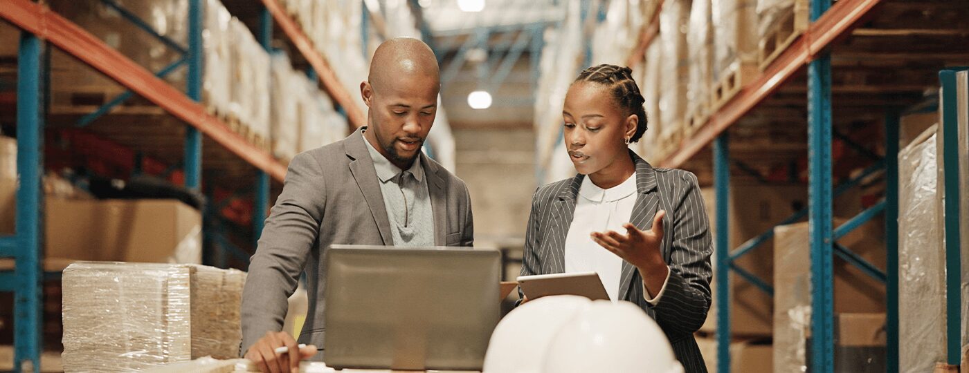 looking at a laptop and tablet. Shelves with boxes line the background
