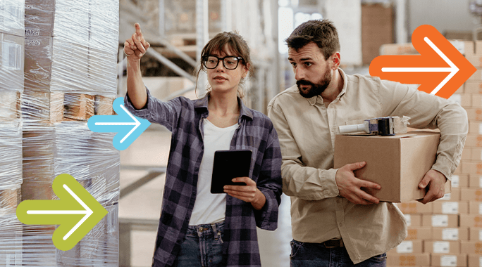 A woman holding a tablet points at stacked boxes wrapped in plastic