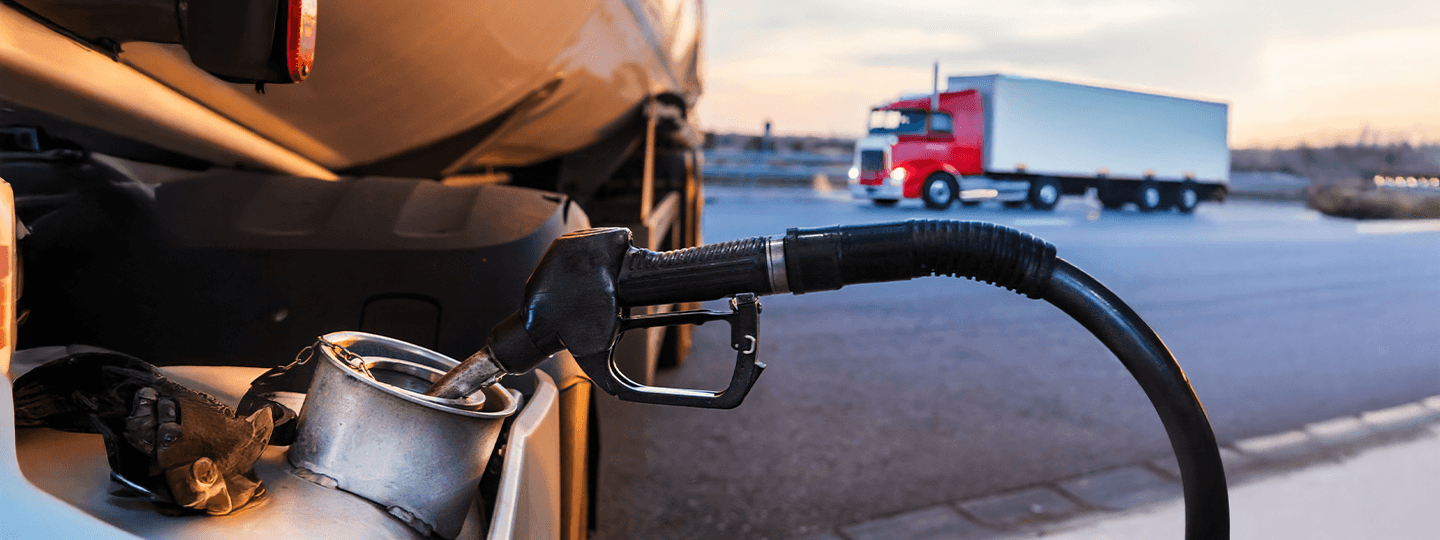 with a red truck and a blue chevron graphic overlay in the background.|A close-up of a fuel nozzle refueling a truck
