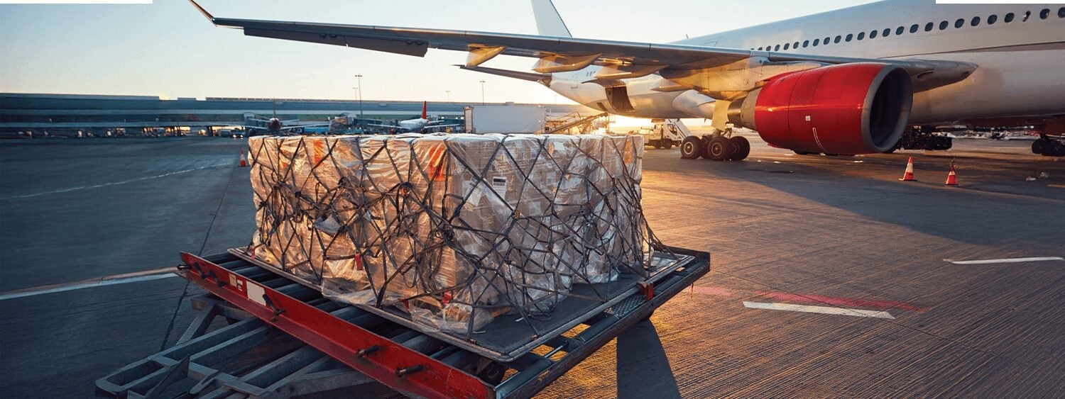 a cargo airplane is parked at an airport during sunset. In the foreground