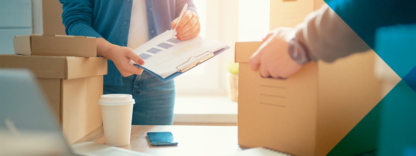 two people manage boxes with precision. One holds a clipboard
