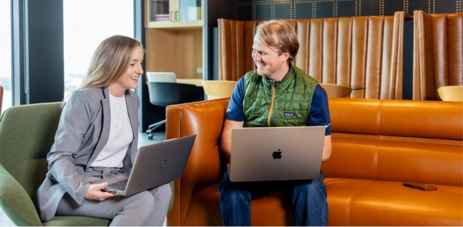 Two people with laptops in a office.