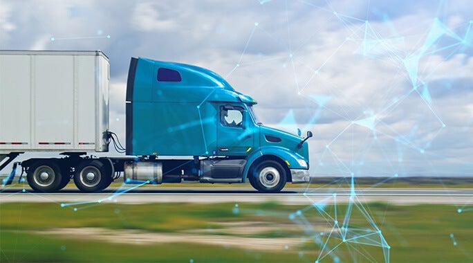 A blue semi-truck drives on a highway under a cloudy sky, with digital network graphics overlaid, highlighting technology in specialty freight transportation and logistics.