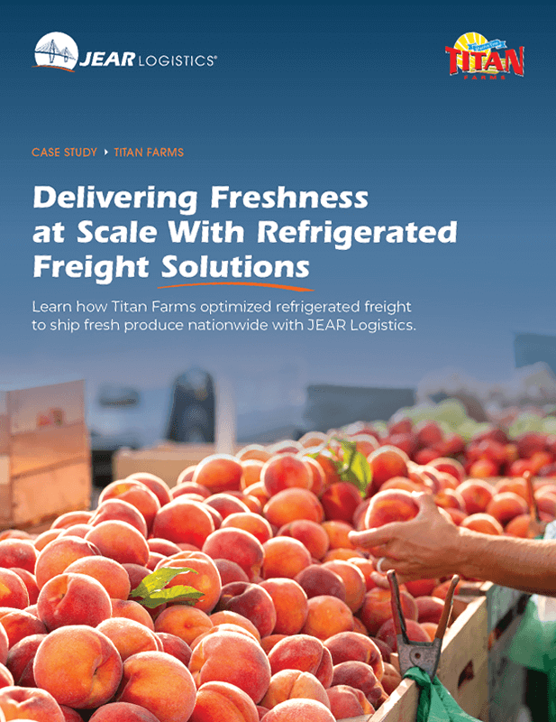 A man holding an apple in front of a pile of fruit.