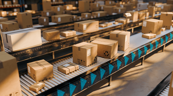 Multiple cardboard boxes move along automated conveyor belts in a warehouse, illuminated by bright overhead lighting. The scene suggests a busy manufacturing supply chain or shipping operation in action.