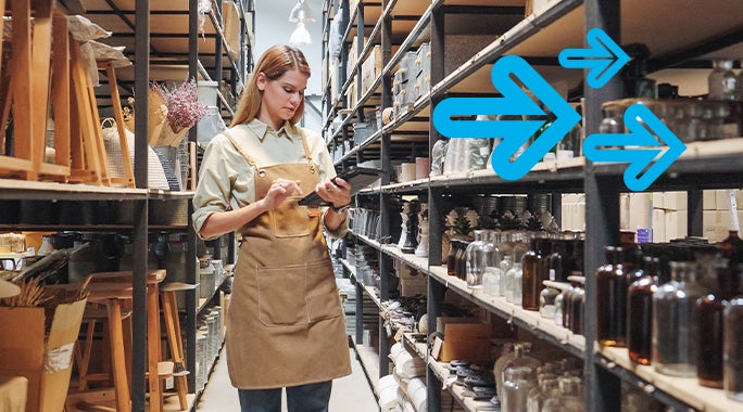 A woman in an apron checks inventory on a digital tablet in a warehouse aisle lined with shelves. Blue arrows are overlaid, pointing right, suggesting movement or direction, as she efficiently tracks items eligible for a potential tariff refund.